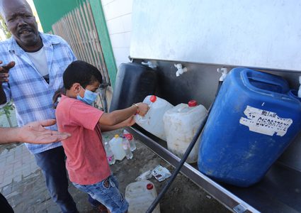 فلسطينيون يملأون الزجاجات من صنبور عام خلال فترة الاغلاق في غزة
