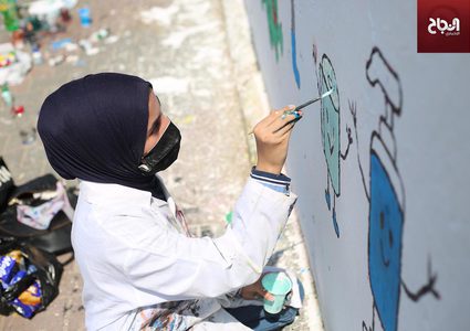 فنانون يرسمون جدارية للتوعية من فيروس كورونا في دير البلح