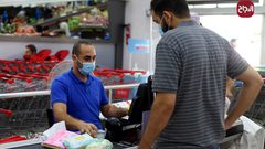مواطنون يلتزمون بارتداء الكمامات أثناء التسوق بغزة بسبب انتشار فيروس كورونا