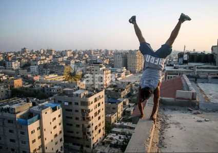 لاعبو باركور فلسطينيون يرتدون أقنعة ويظهرون مهاراتهم على سطح مبنى في مدينة غزة