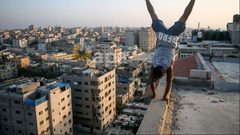لاعبو باركور فلسطينيون يرتدون أقنعة ويظهرون مهاراتهم على سطح مبنى في مدينة غزة