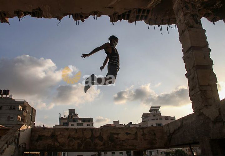 لاعبو باركور فلسطينيون يرتدون أقنعة ويظهرون مهاراتهم على سطح مبنى في مدينة غزة