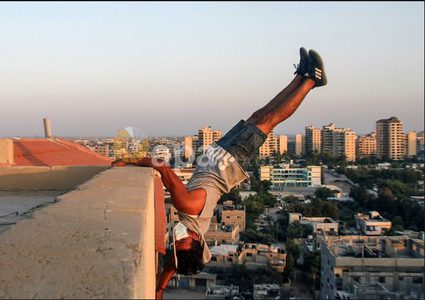 لاعبو باركور يرتدون أقنعة ويظهرون مهاراتهم على سطح مبنى بغزة