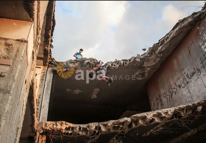 لاعبو باركور فلسطينيون يرتدون أقنعة ويظهرون مهاراتهم على سطح مبنى في مدينة غزة