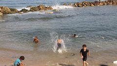 أطفال يسبحون على شاطىء البحر بمخيم الشاطئ غرب غزة