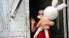 طفلة فلسطينية تحمل دميتها تقف على باب منزلها وسط تفشي مرض فيروس كورونا (COVID-19) في جباليا شمال قطاع غزة
