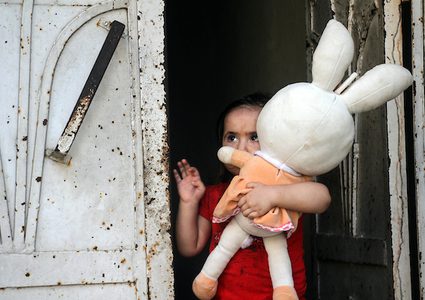 طفلة فلسطينية تحمل دميتها تقف على باب منزلها وسط تفشي مرض فيروس كورونا (COVID-19) في جباليا شمال قطاع غزة