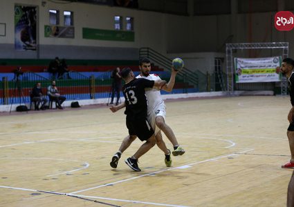 لاعبو كرة يد فلسطينيون من اتحاد دير البلح (أبيض) وخدمة البريج (أسود) يتنافسون خلال نهائي الكأس في صالة سعد صايل للألعاب الرياضية في غزة