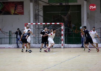 لاعبو كرة يد فلسطينيون من اتحاد دير البلح (أبيض) وخدمة البريج (أسود) يتنافسون خلال نهائي الكأس في صالة سعد صايل للألعاب الرياضية في غزة