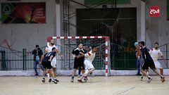 لاعبو كرة يد فلسطينيون من اتحاد دير البلح (أبيض) وخدمة البريج (أسود) يتنافسون خلال نهائي الكأس في صالة سعد صايل للألعاب الرياضية في غزة