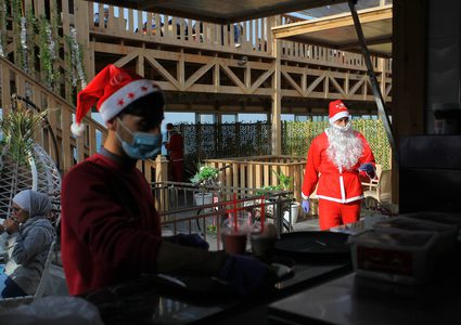 موظفون يرتدون زي "سانتا كلوز" في مقهى على شاطئ مدينة غزة