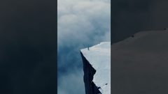 امرأة تسير على حافة جبل مغطى بالثلج