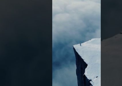 امرأة تسير على حافة جبل مغطى بالثلج