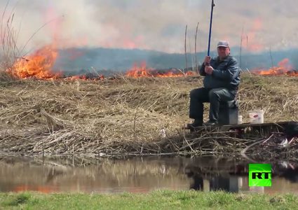 رجل يواصل صيد الأسماك رغم حريق يقترب منه