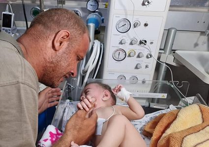 الفلسطيني محمد الحديدي يقبل يد طفله الناجي من مجـزرة الشاطئ