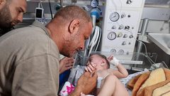 الفلسطيني محمد الحديدي يقبل يد طفله الناجي الوحيد من مجـزرة الشاطئ في غزة والتي راح ضحيتها 10 شهداء بينهم اطفال ونساء