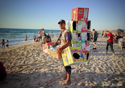 شاب مكافح يحمل بقالة من "الشبس" على ظهره لكسب لقمة العيش على شاطىء بحر محافظة خان يونس جنوبي قطاع غزة، تصوير هاني الشاعر