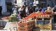 فلسطينيون يتسوقون من سوق مخيم النصيرات بين الدمار والركام