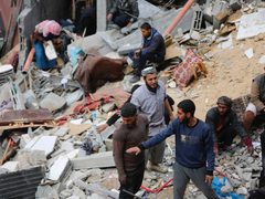 فلسطينيون يحاولون تفقد ما تبقى من منازلهم التي دمرتها غارات الاحتلال الإسرائيلي على دير البلح وسط قطاع غزة.