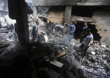 فلسطينيون يحاولون تفقد ما تبقى من منازلهم التي دمرتها غارات الاحتلال الإسرائيلي على دير البلح وسط قطاع غزة.