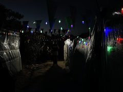 أطفال ونساء فلسطينيون ينظرون إلى زينة رمضان التي تم تعليقها خارج خيام نازحين في مدينة دير البلح وسط قطاع غزة رغم الظروف الصعبة التي يعيشونها بسبب الحرب المتواصلة