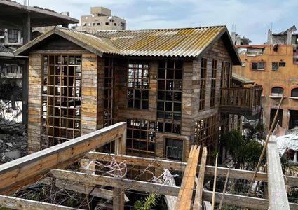 شاب يبني كوخًا خشبيًا مكان منزل مدمر بعزة