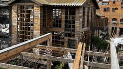 شاب يبني كوخًا خشبيًا مكان منزل مدمر بعزة