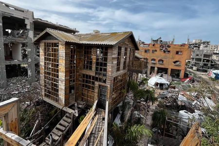 شاب يبني كوخًا خشبيًا مكان منزل مدمر بعزة