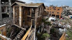 شاب يبني كوخًا خشبيًا مكان منزل مدمر بعزة