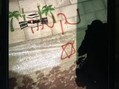 آثار إحراق المستوطنين مركبة فلسطينية وكتابة شعارات عنصرية على الجدران في منطقة صافا ببلدة بيت أمر شمال الخليل.