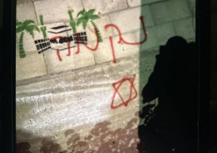 آثار إحراق المستوطنين مركبة فلسطينية وكتابة شعارات عنصرية على الجدران في منطقة صافا ببلدة بيت أمر شمال الخليل.